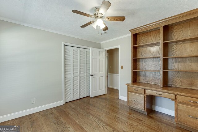 unfurnished office with crown molding, a ceiling fan, light wood-type flooring, baseboards, and a textured ceiling