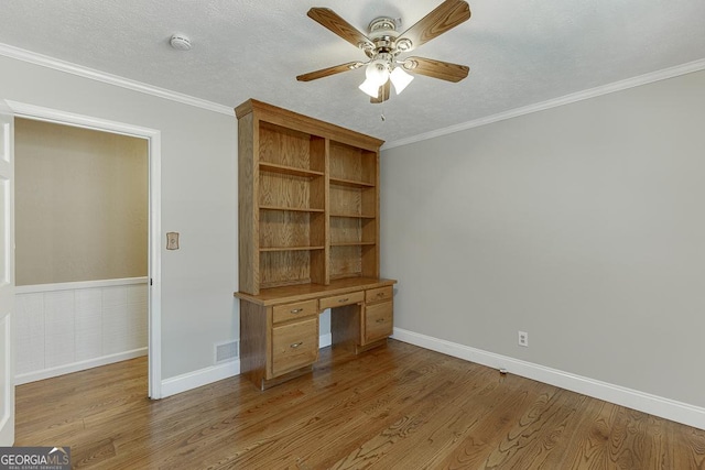 unfurnished office featuring wood finished floors, ceiling fan, ornamental molding, and baseboards