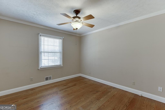 spare room with wood finished floors, ceiling fan, baseboards, a textured ceiling, and crown molding