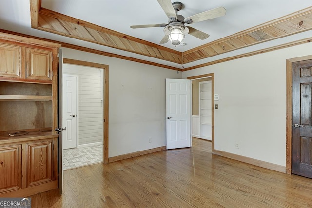 unfurnished bedroom with light wood-style floors, baseboards, a tray ceiling, and a ceiling fan