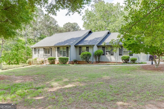 ranch-style house featuring board and batten siding, covered porch, a front yard, and a garage