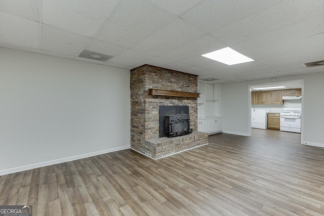 unfurnished living room with wood finished floors, baseboards, and a drop ceiling