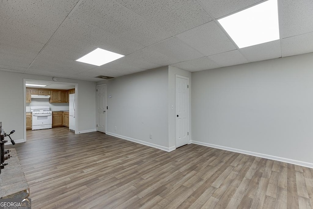 unfurnished living room featuring wood finished floors, baseboards, and a drop ceiling