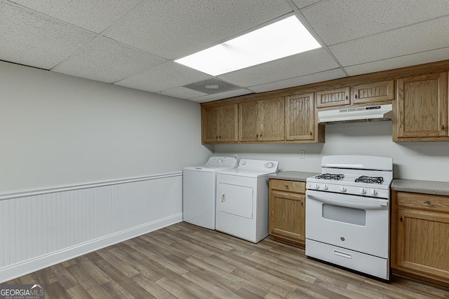 laundry area featuring washer and dryer, light wood-style floors, and a wainscoted wall