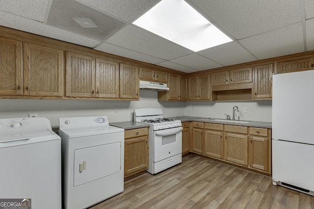 kitchen with white appliances, under cabinet range hood, washer and clothes dryer, a paneled ceiling, and a sink