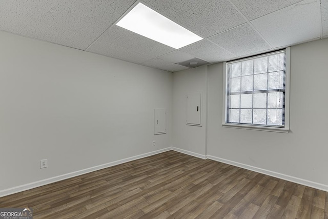 empty room with dark wood-style floors, baseboards, and a drop ceiling