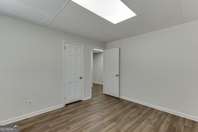 unfurnished room featuring wood finished floors, baseboards, and a paneled ceiling