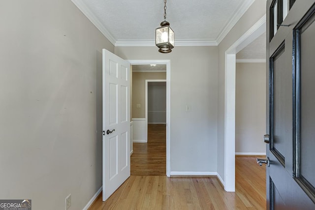 entrance foyer with light wood-style flooring, ornamental molding, baseboards, and a textured ceiling
