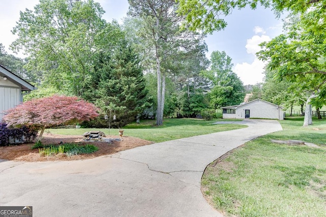 view of community featuring a yard, concrete driveway, and view of scattered trees