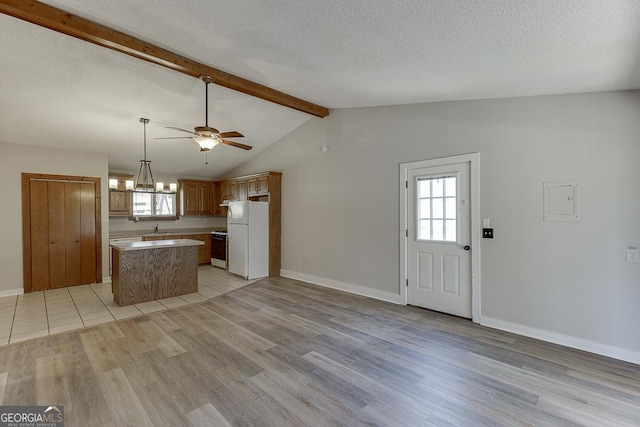 kitchen featuring freestanding refrigerator, a sink, plenty of natural light, light wood-type flooring, and a textured ceiling