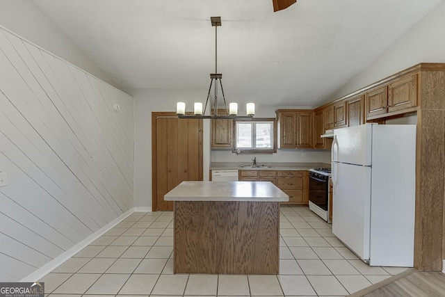 kitchen with white appliances, a sink, light countertops, a kitchen island, and light tile patterned floors