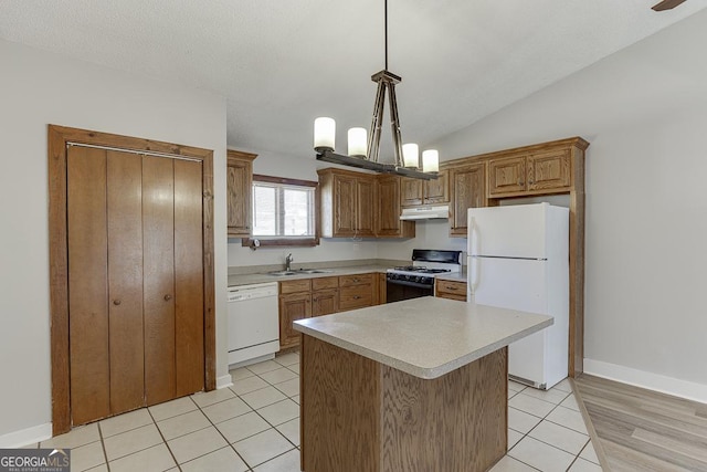 kitchen with white appliances, a sink, under cabinet range hood, light countertops, and decorative light fixtures