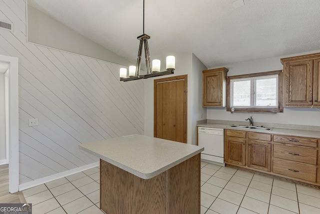 kitchen with dishwasher, a sink, light tile patterned floors, light countertops, and wood walls