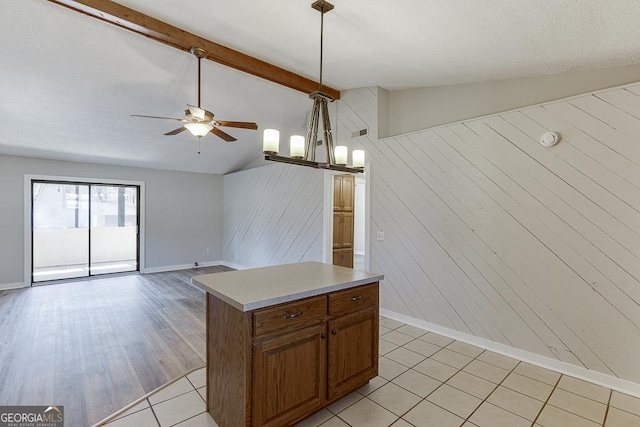 kitchen with ceiling fan, baseboards, wood walls, light countertops, and brown cabinetry