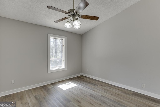 empty room with wood finished floors, a textured ceiling, baseboards, and ceiling fan