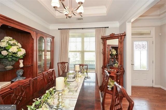 dining space featuring a tray ceiling, visible vents, a notable chandelier, and wood finished floors