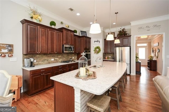 kitchen with light wood-style flooring, a kitchen bar, appliances with stainless steel finishes, and a sink