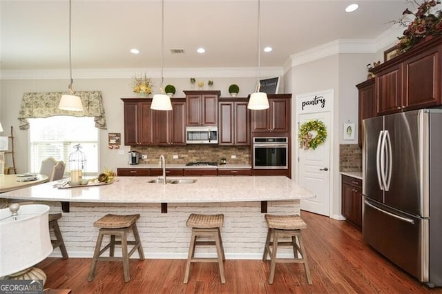 kitchen featuring appliances with stainless steel finishes, a kitchen bar, dark wood finished floors, and visible vents