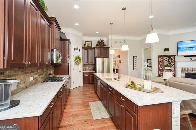 kitchen featuring stainless steel appliances, crown molding, light wood-style floors, a kitchen bar, and a sink