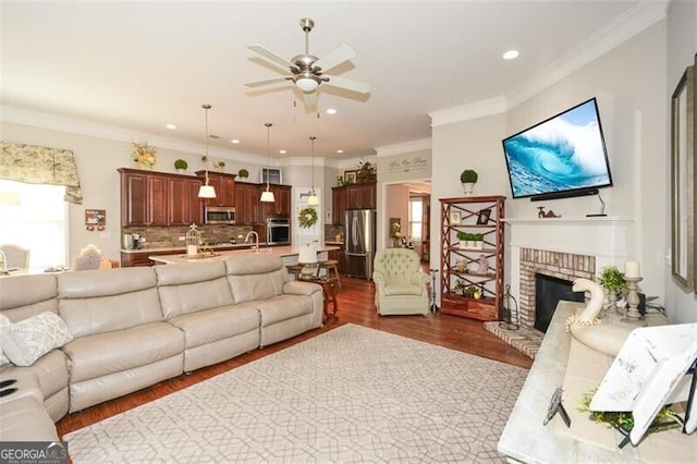 living area featuring dark wood-style floors, a fireplace, recessed lighting, a ceiling fan, and ornamental molding