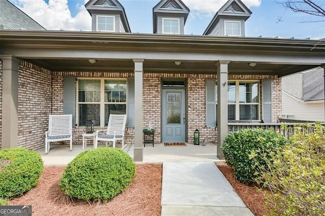 view of exterior entry with covered porch and brick siding