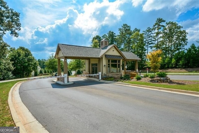 view of front facade featuring aphalt driveway, a chimney, and a shingled roof