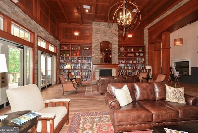 living area featuring a notable chandelier, a large fireplace, a high ceiling, wood finished floors, and built in features