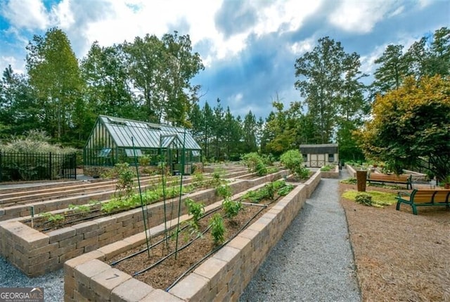 view of community with a greenhouse, a vegetable garden, an outdoor structure, and fence