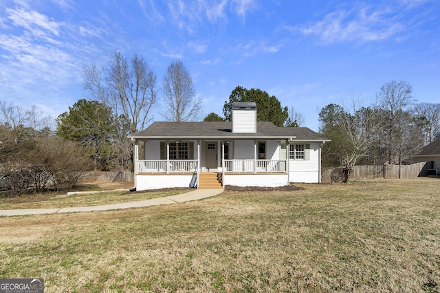 ranch-style house featuring a porch, a chimney, a front yard, and fence