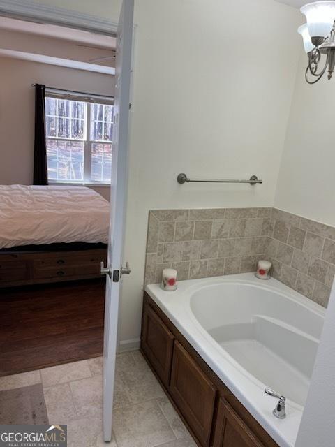 ensuite bathroom featuring an inviting chandelier, ensuite bathroom, and a bath