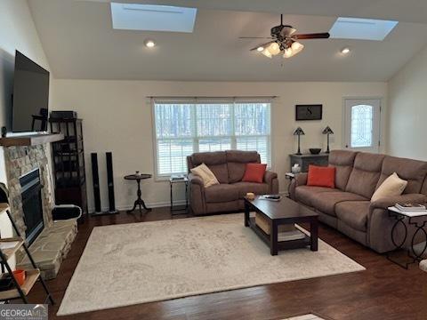 living room with recessed lighting, a fireplace, a ceiling fan, lofted ceiling with skylight, and dark wood finished floors