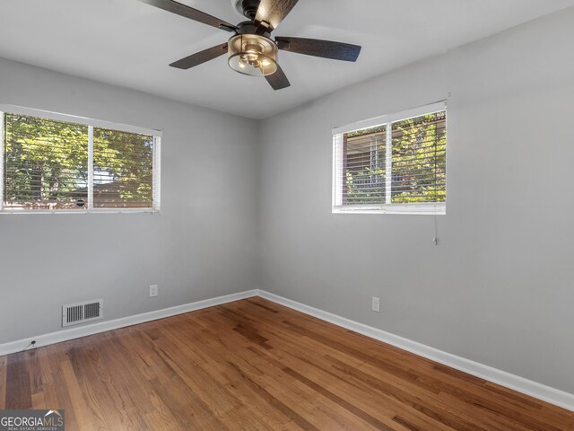 empty room with visible vents, ceiling fan, baseboards, and wood finished floors