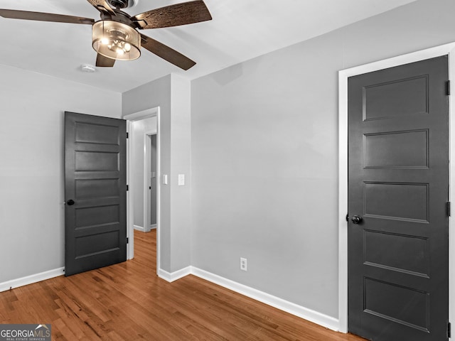 unfurnished bedroom with a ceiling fan, baseboards, and wood finished floors