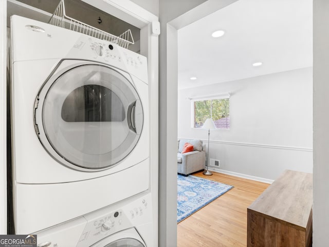 laundry area featuring laundry area, baseboards, stacked washer / dryer, wood finished floors, and recessed lighting