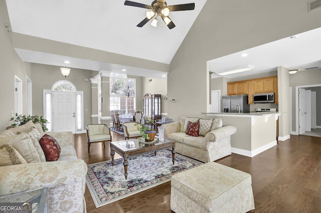 living room featuring visible vents, dark wood-style floors, ceiling fan, ornate columns, and high vaulted ceiling