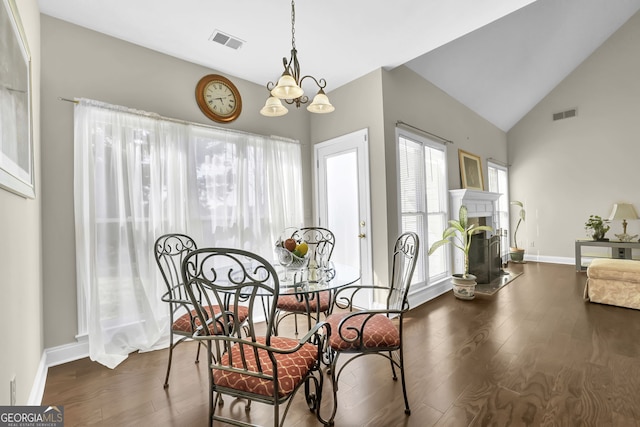 dining area with a fireplace with raised hearth, wood finished floors, and visible vents