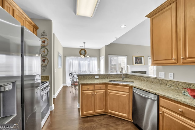 kitchen featuring light stone counters, appliances with stainless steel finishes, dark wood-type flooring, a sink, and a peninsula