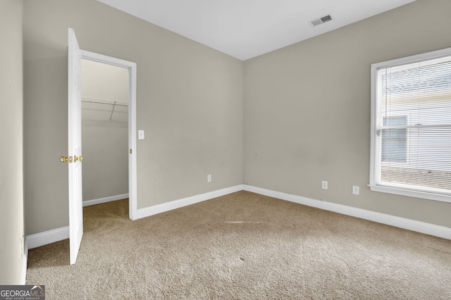 unfurnished bedroom with a closet, visible vents, a spacious closet, carpet flooring, and baseboards