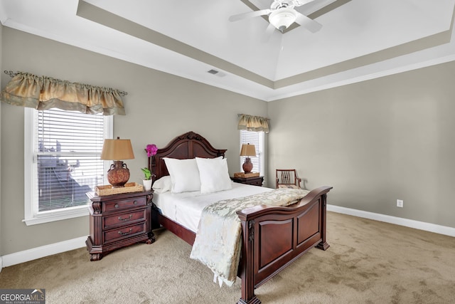 bedroom featuring a tray ceiling, light carpet, visible vents, and baseboards