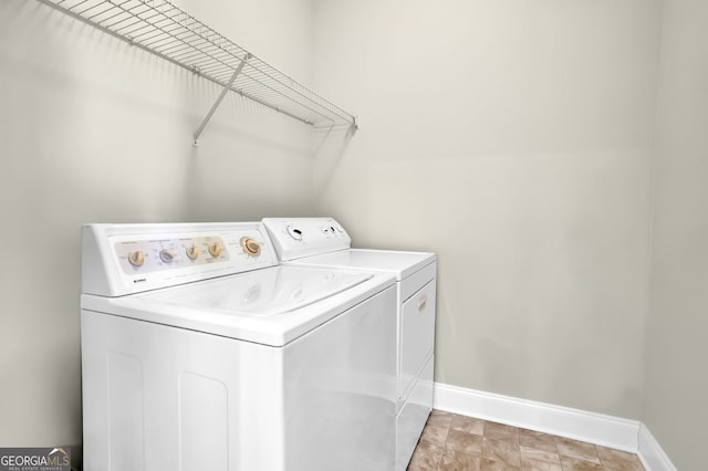 clothes washing area featuring laundry area, washing machine and clothes dryer, and baseboards