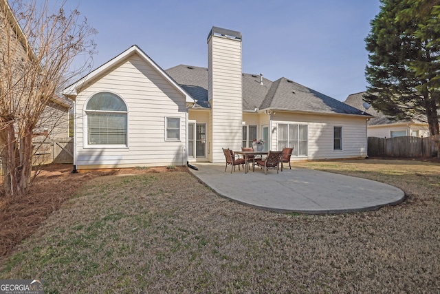 back of house with a chimney, a patio, a lawn, and fence