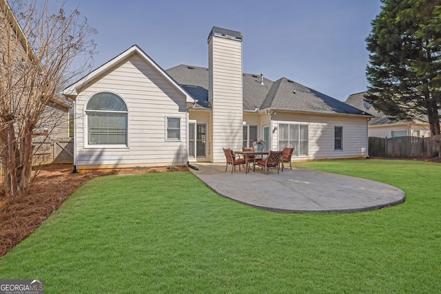 rear view of property featuring a lawn, a patio, a chimney, roof with shingles, and fence