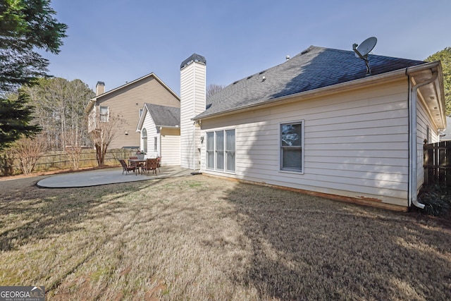 back of property featuring a patio, a shingled roof, a lawn, and fence