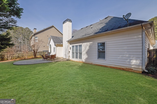 back of property featuring a patio, a shingled roof, a lawn, and fence