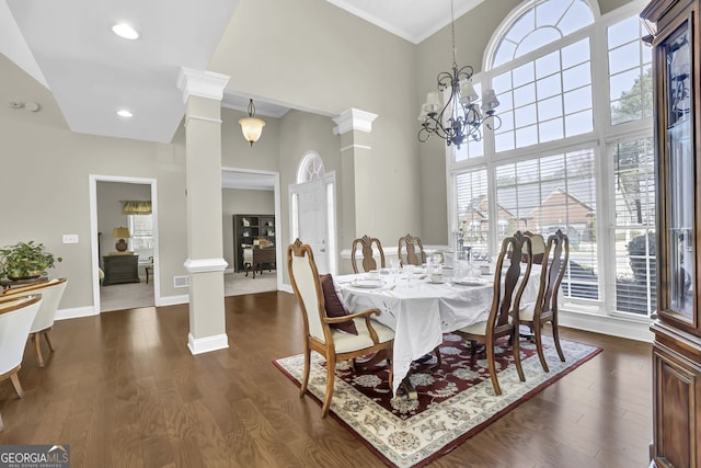 dining space featuring dark wood-style floors, a chandelier, baseboards, and ornate columns