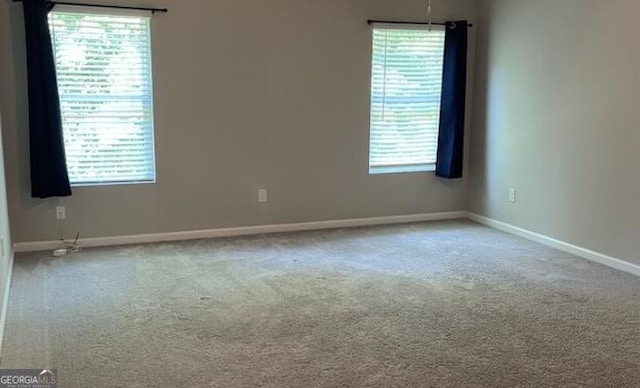 unfurnished room with a wealth of natural light, carpet flooring, and baseboards