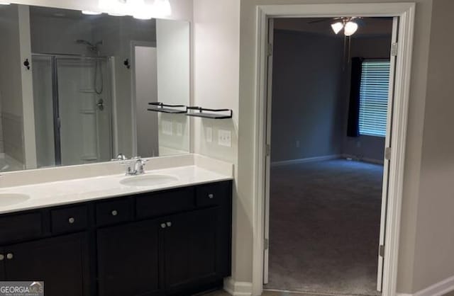 full bathroom with a sink, a shower stall, baseboards, and double vanity