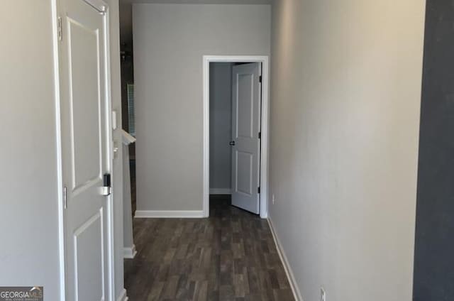 corridor featuring baseboards and dark wood-type flooring