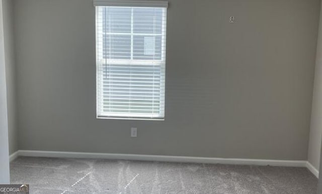 carpeted spare room featuring a healthy amount of sunlight and baseboards