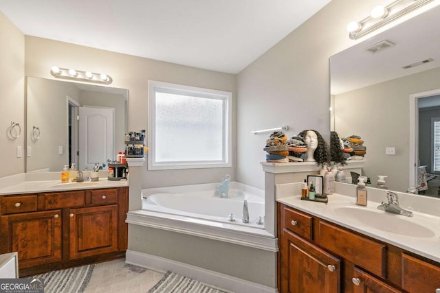 bathroom featuring visible vents, two vanities, a sink, and a bath